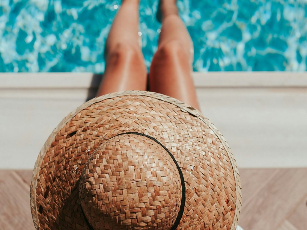 A woman in a straw hat relaxing by a pool